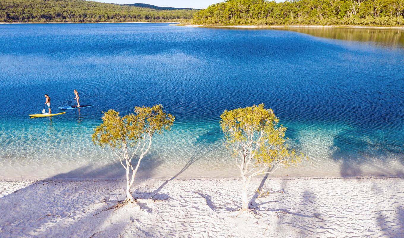 Couple stand up paddle boarding on Lake Mckenzie, Australia