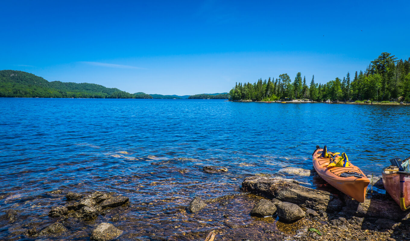 Kayak and canoe on the blue waters of Lac du Poisson Blanc, Outaouais region of Quebec province