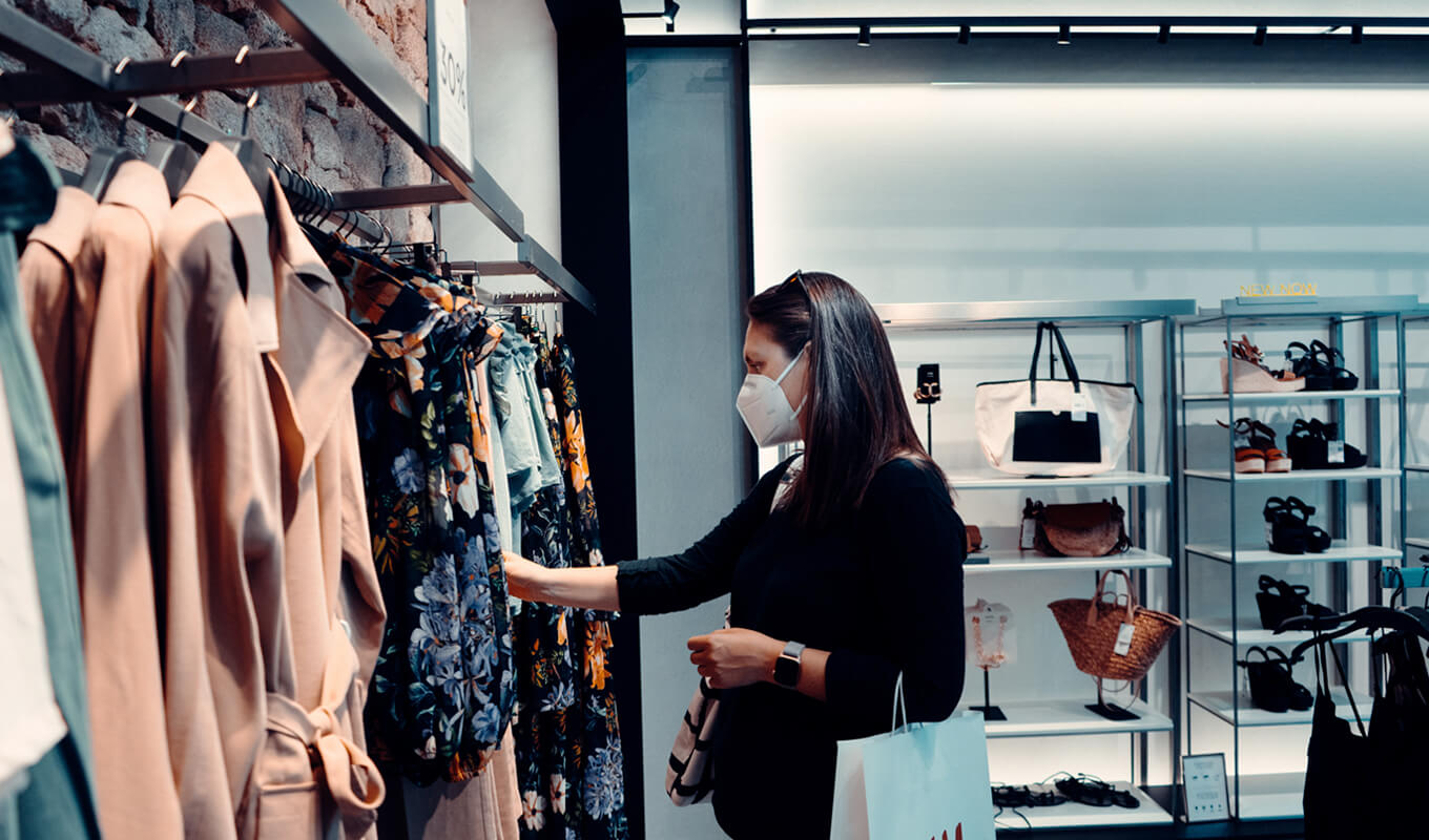 Woman standing in front of clothes at shopping mall 