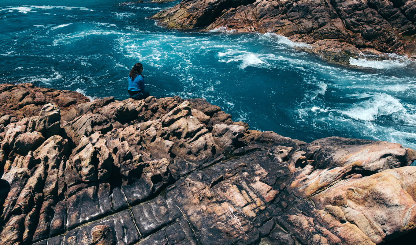 Woman sitting on the rock while looking on the Margaret river, Western Australia