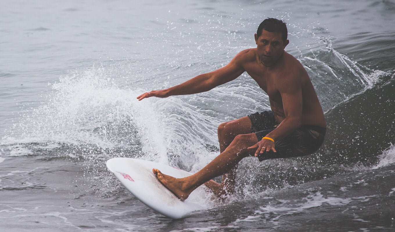 Topless man surfing on Buccaneer Archipelago, Western Australia