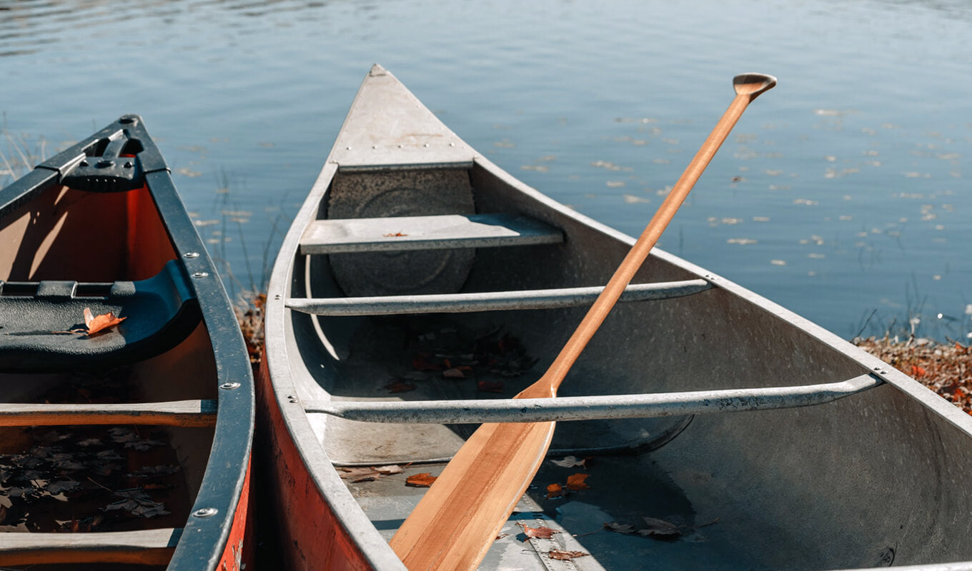 Red aluminum canoe with a wooden paddle