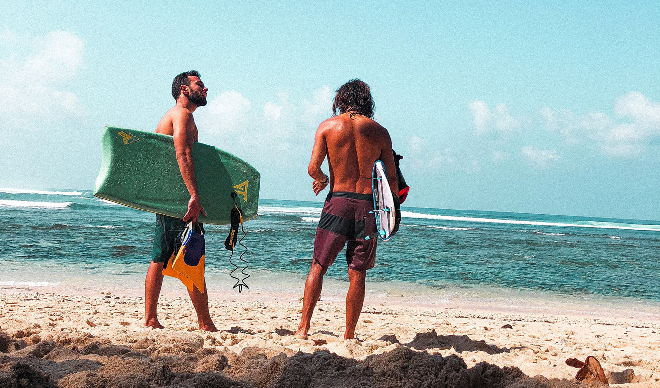 Two men holding their boogie boards at the beach