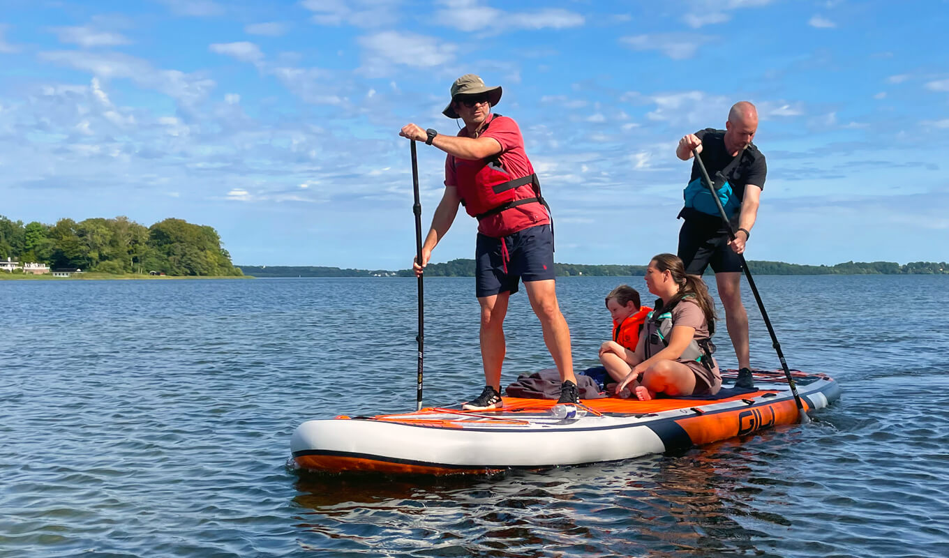 Group of people riding a large inflatable paddle board