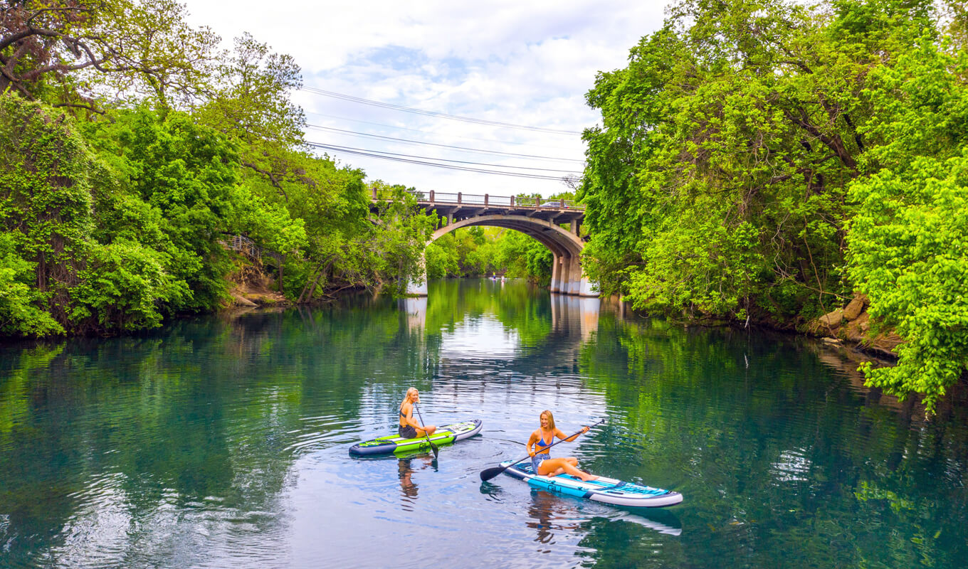 Two women paddle boarding in river