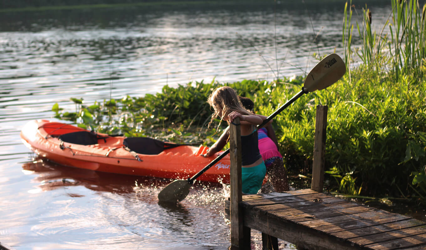kids riding an orange kayak in the lake
