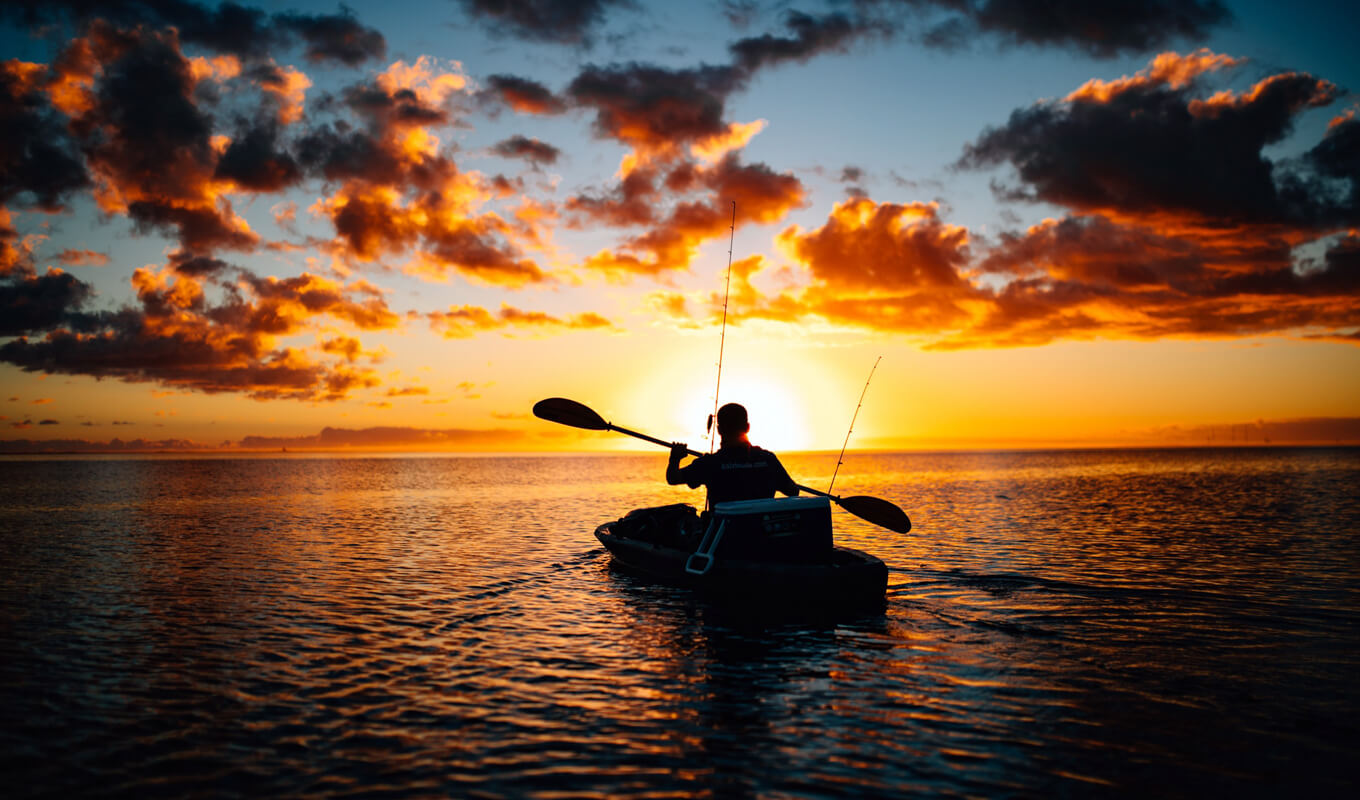Man kayaking on sea while sunset
