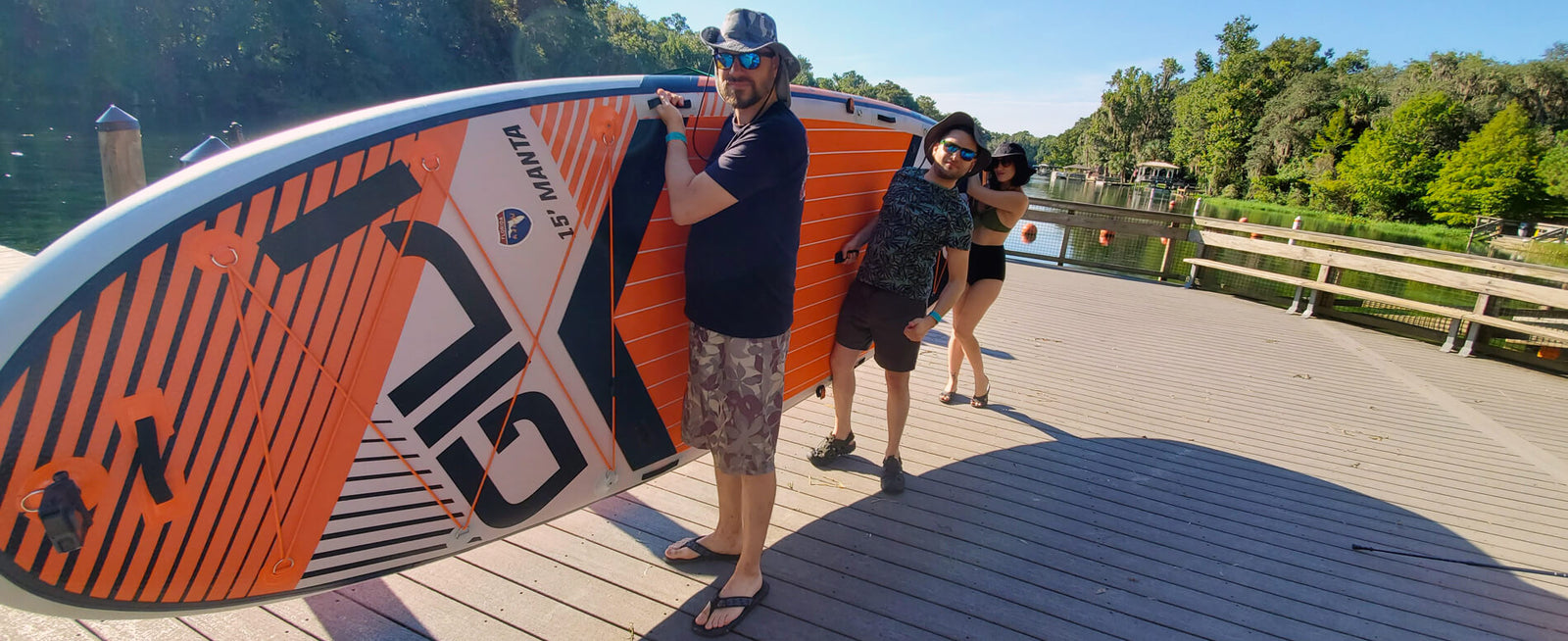 A group of friends holding a multi person inflatable paddle board