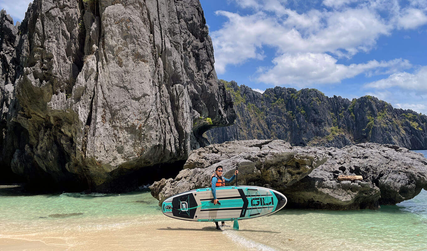 Man wearing a life jacket carrying his inflatable paddle board