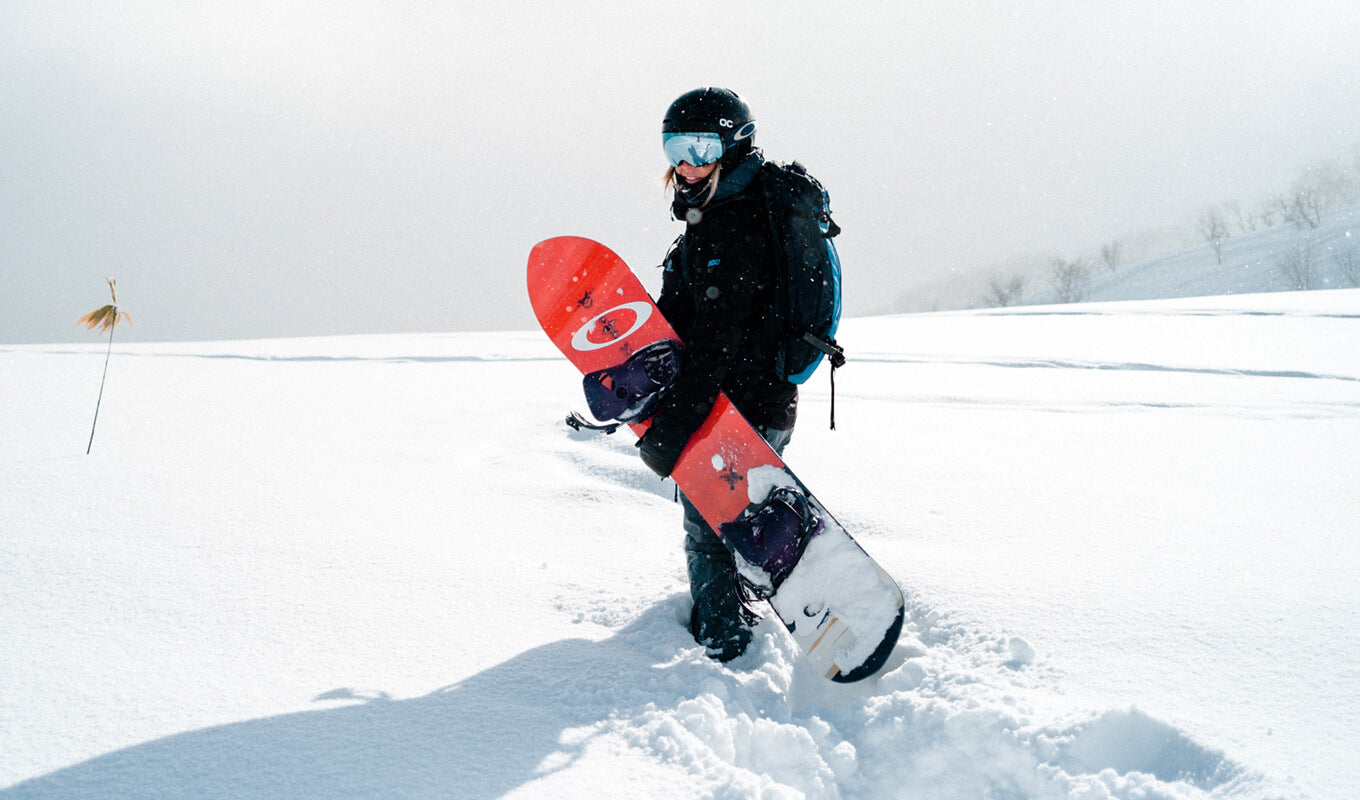 Man holding a snowboard and wearing goggles