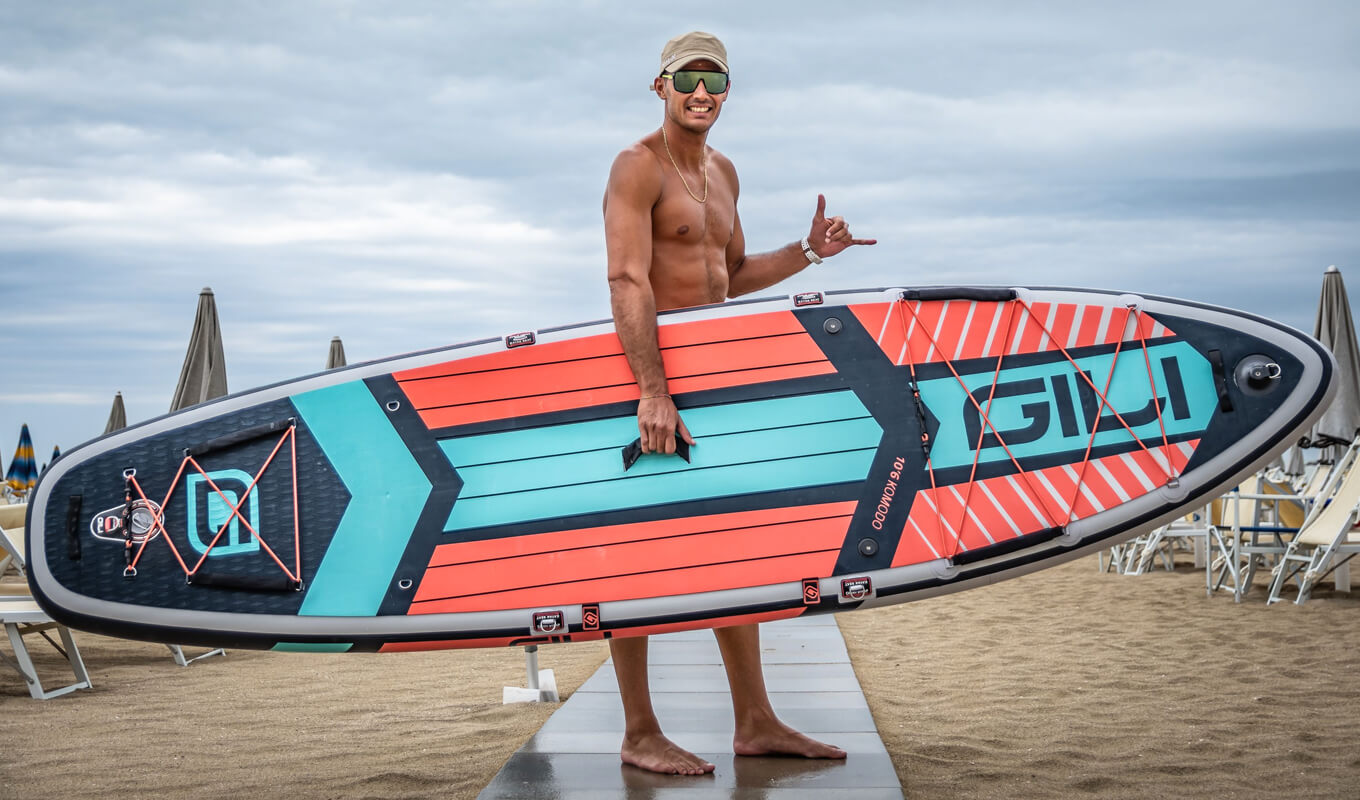 Man wearing a sunglasses and holding a gili komodo inflatable paddle board