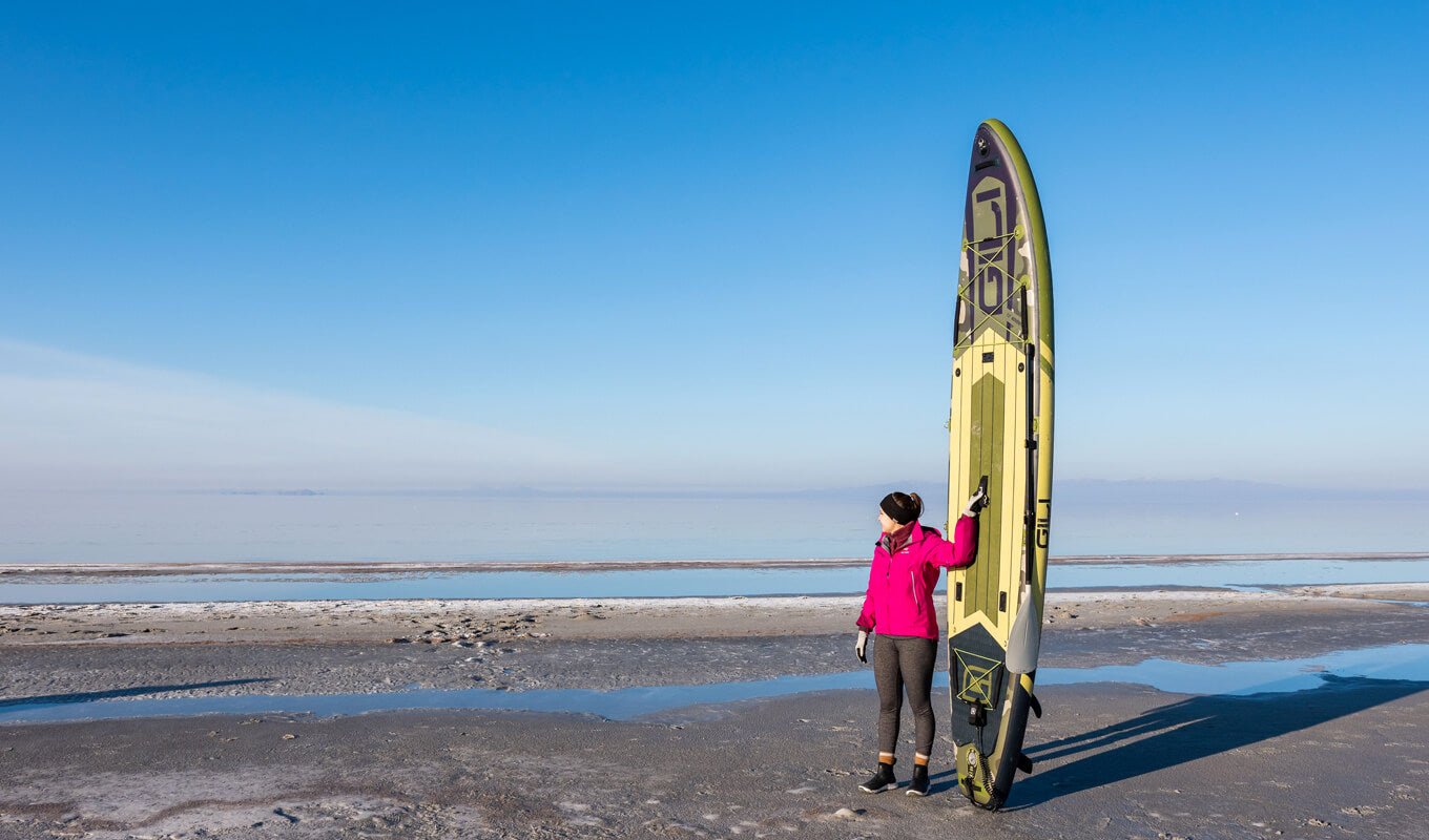 Woman wearing a red jacket holding her Gili adventure inflatable paddle board