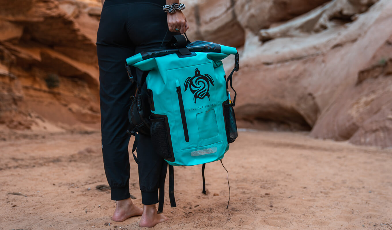 Woman holding a teal roll top waterproof backpack